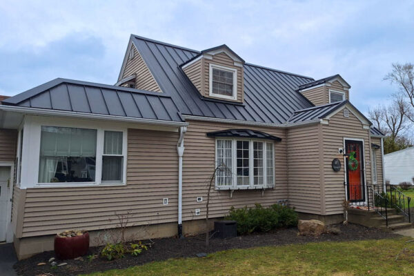 Completed dark gray standing seam metal roof installation on a residential home with multiple dormers in Fredonia, NY.