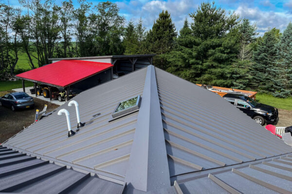 Gray standing seam metal roof installation featuring a built-in skylight and custom ridge cap, completed in Cassadaga, NY by MW Home Improvements.