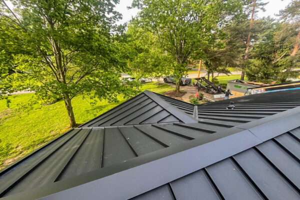 Close-up of expert flashing and valley detail on a new black metal roof replacement.