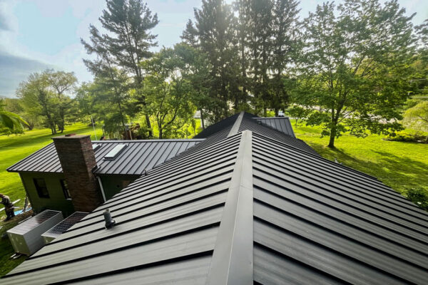 Completed premium residential standing seam metal roof project with clean ridge caps.
